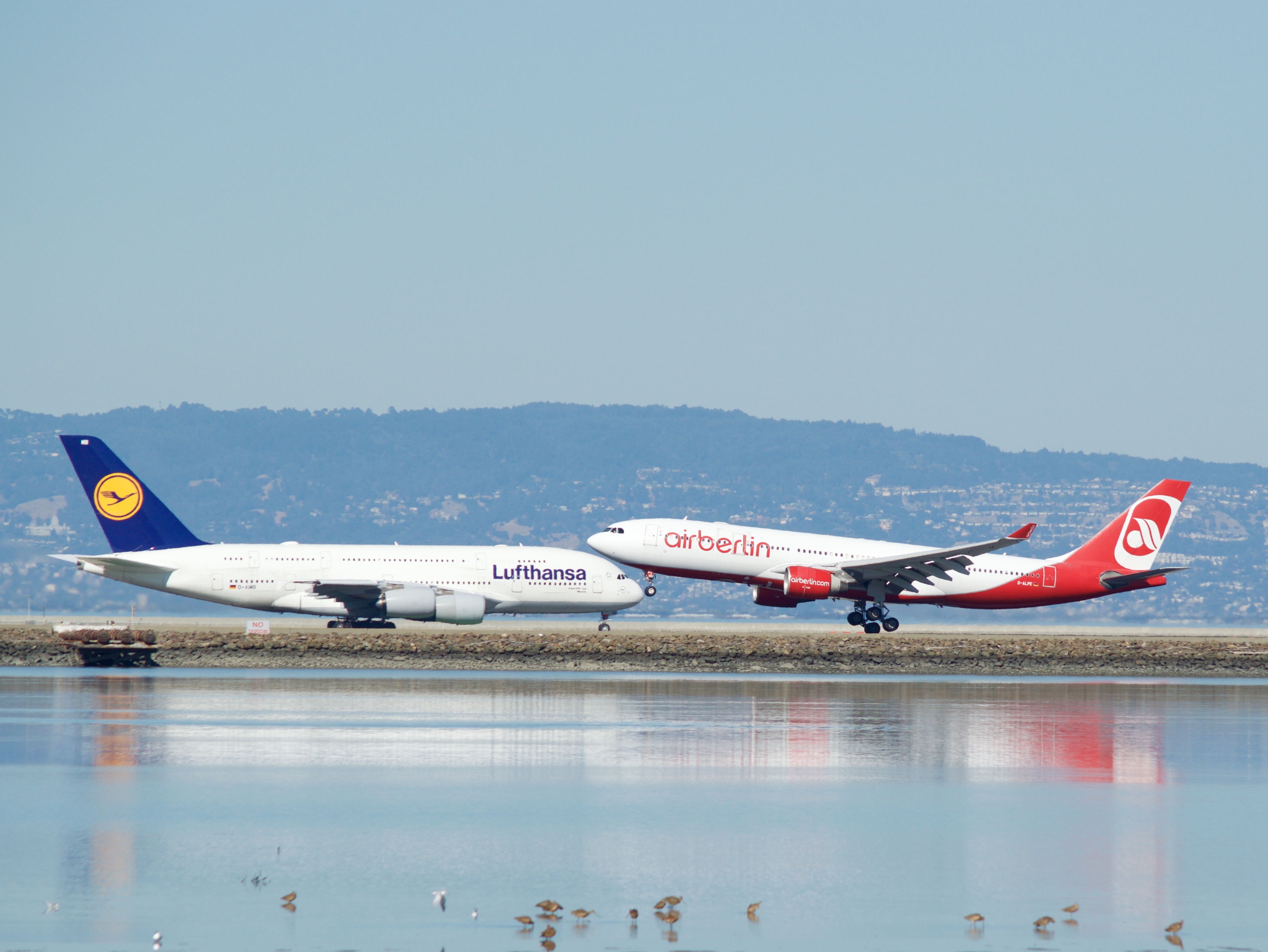 Air_Berlin_A-330_landing_Lufthansa_Airbus_A-380_taxiing_to_takeoff_runway_28_SFO_(30144412484)